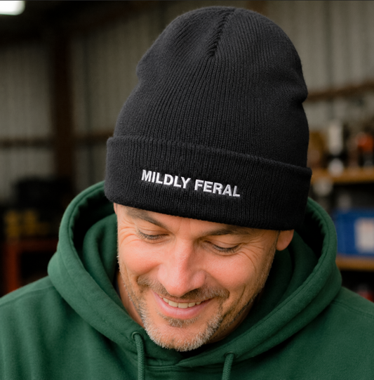 Man wearing a black beanie with 'Mildly Feral' text in an indoor setting
