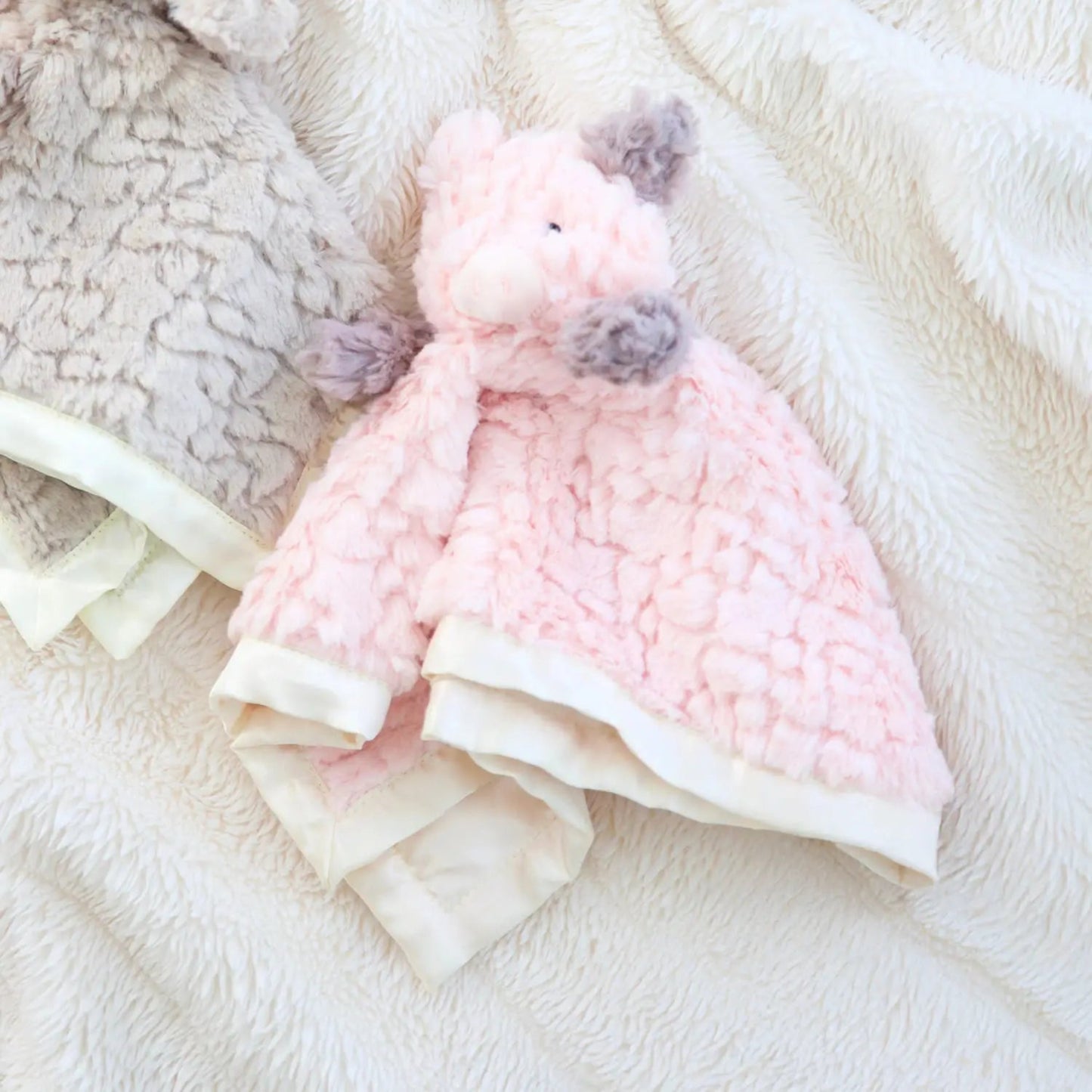 Pink plush toy with pom-poms on a soft white surface