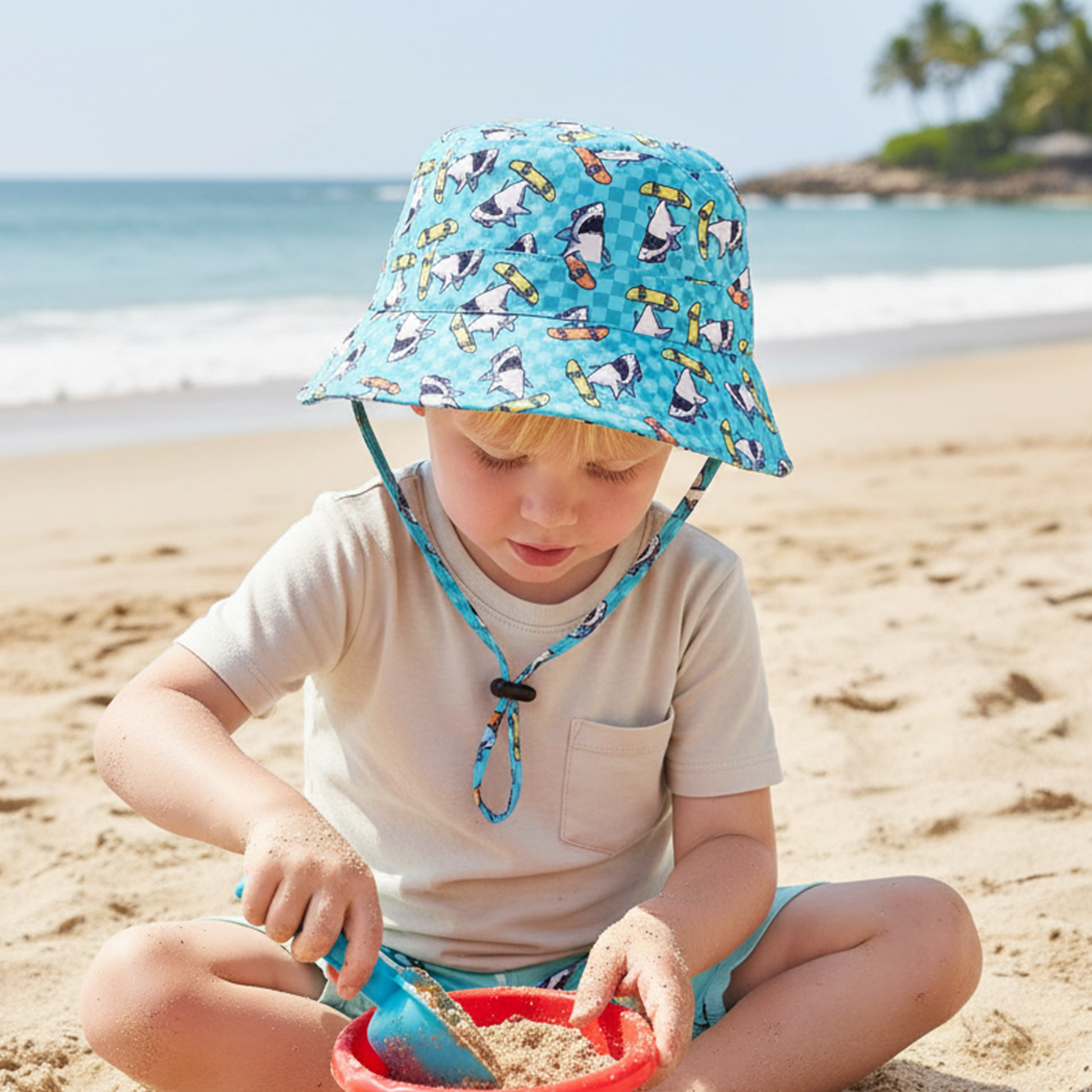 Child playing on a sandy beach with sand toys and a colorful hat.