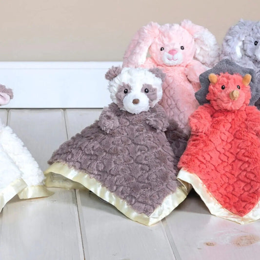 Plush toys with textured blankets on a light surface