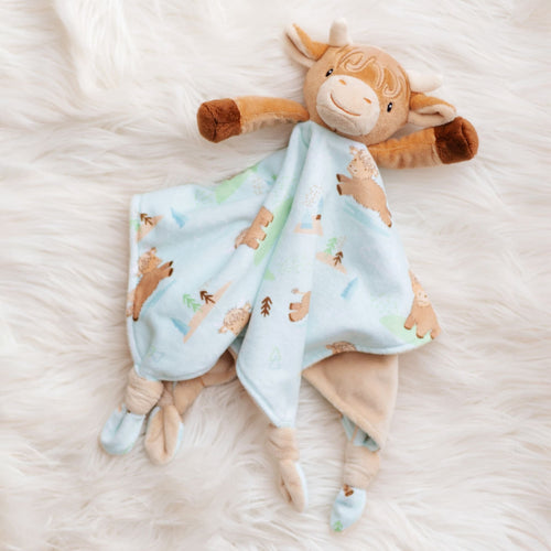 Plush toy cow with a matching blanket on a soft white surface