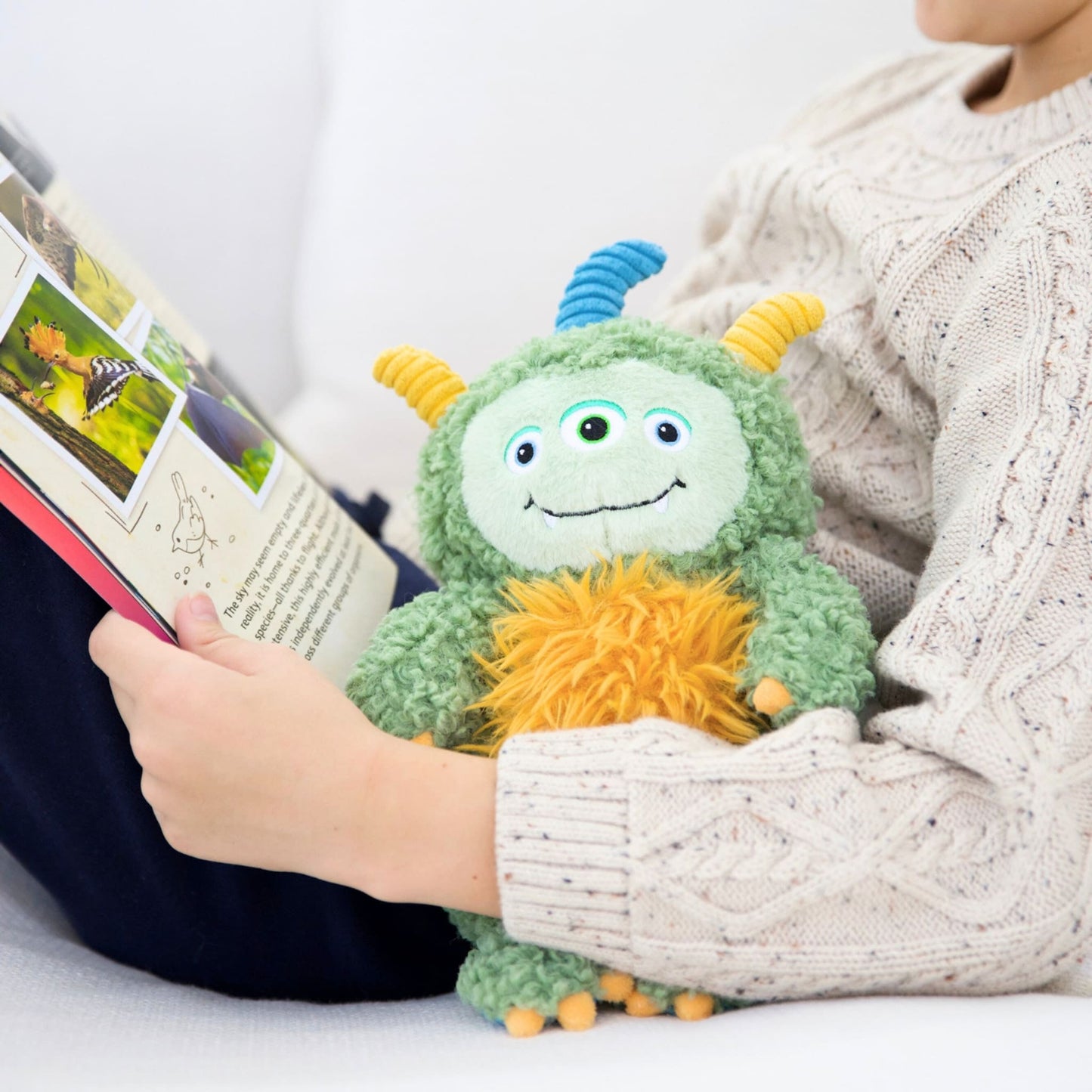 Child holding a plush toy and a book on a white surface